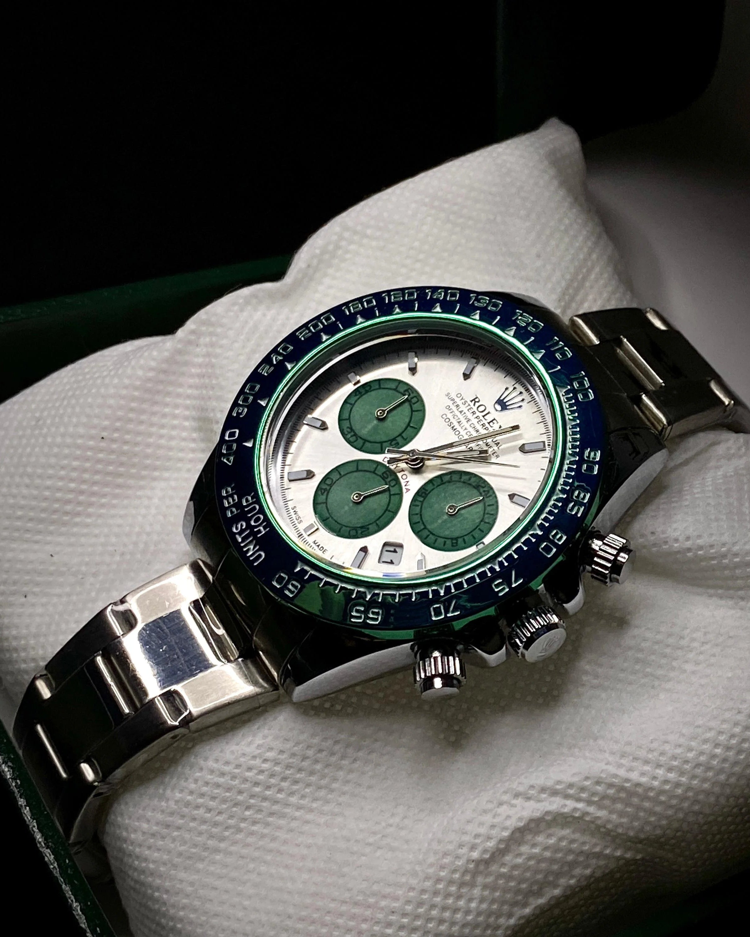 Rolex watch with green face and black strap on a white cloth